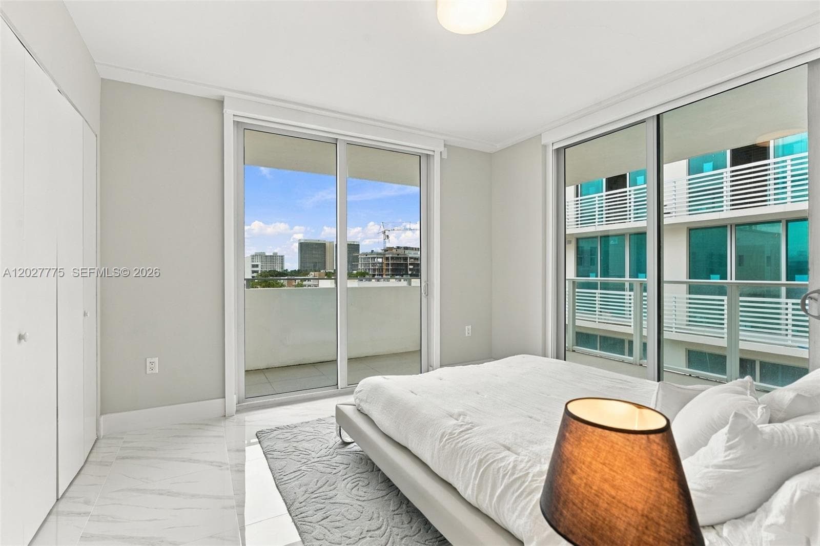 White marble-look tile flooring, built-in closet, sliding glass doors, white walls, recessed lighting