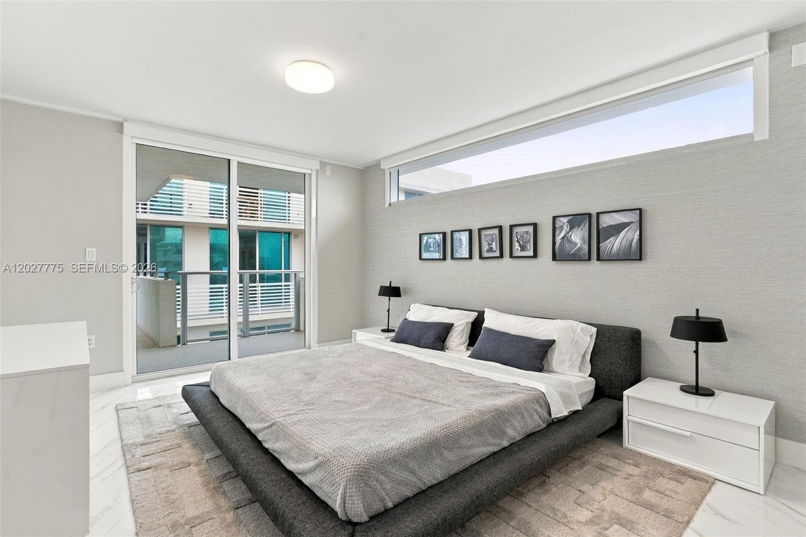 Sliding glass doors opening to a balcony, high transom window, light-toned textured wall covering, and recessed ceiling lighting