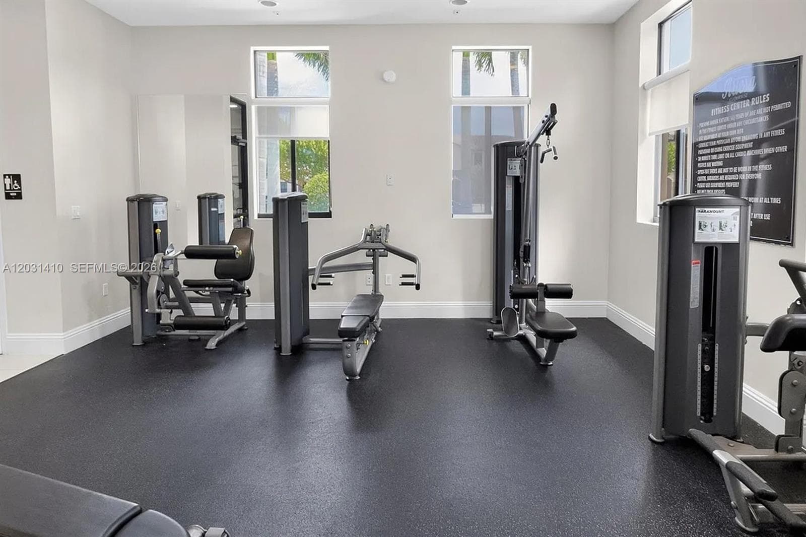 Fitness facility featuring durable rubberized flooring, high-contrast wall finishes, and multiple large-format windows with integrated roller shades