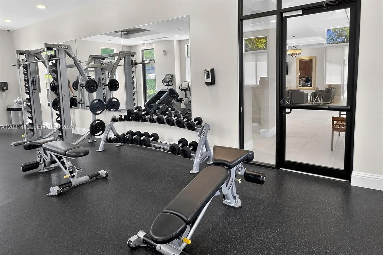 Fitness center featuring rubberized flooring, floor-to-ceiling wall mirror, recessed lighting, and a glass-paneled entry door