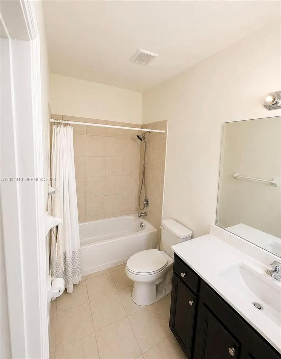Bathroom featuring a vanity with a white countertop and rectangular undermount sink, dark-finish cabinetry, tile flooring, and a shower-tub combination with tile surround
