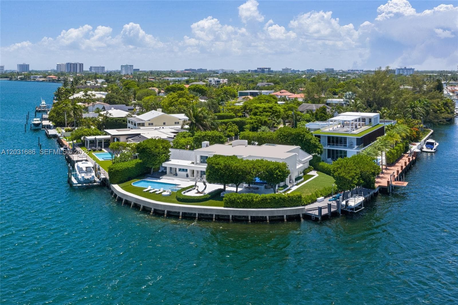 Waterfront property featuring a private boat dock, swimming pool, manicured lawn, and extensive sea wall