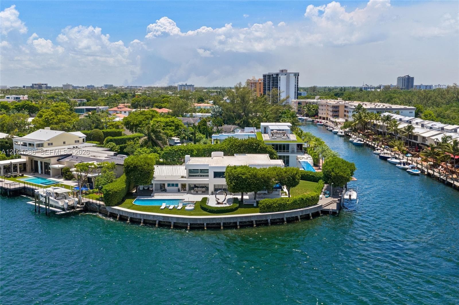 Waterfront residence featuring a private boat dock, swimming pool, manicured lawn, and extensive sea wall