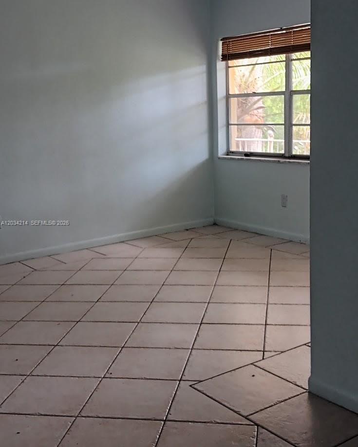 Interior space featuring neutral-toned tile flooring laid on the diagonal and a multi-pane window with attached wood-slat blinds