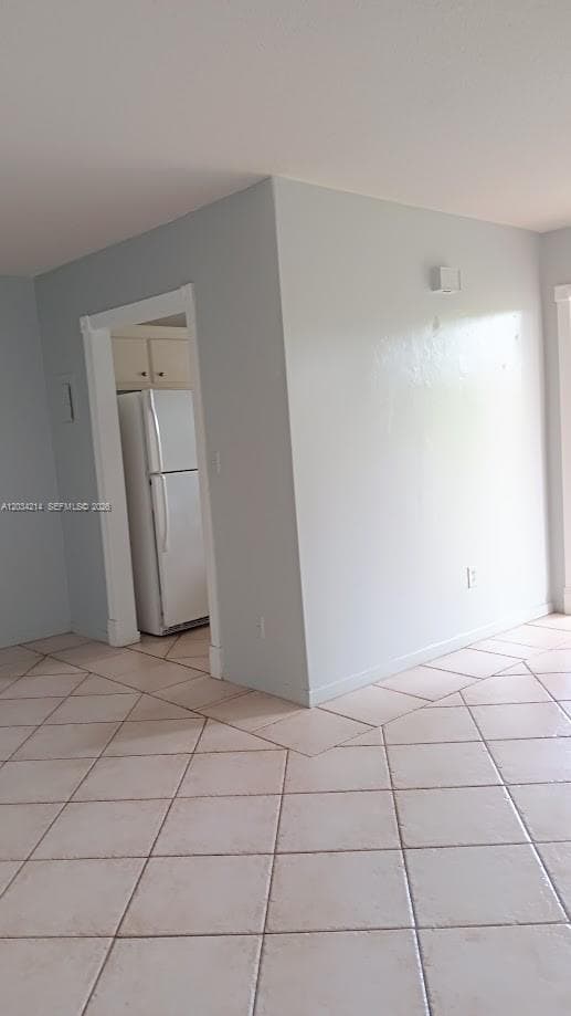 Neutral-toned interior featuring square ceramic tile flooring, solid-surface walls, and a built-in refrigerator