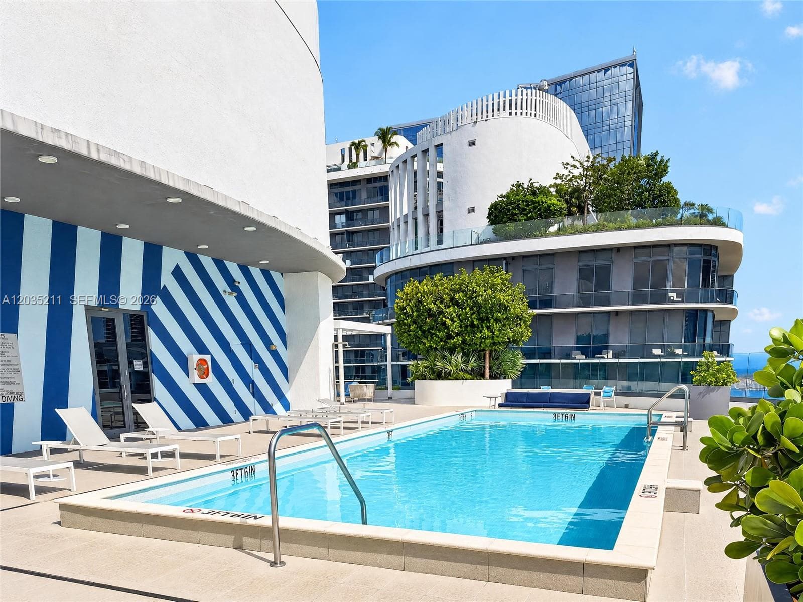 Outdoor swimming pool featuring a concrete deck, built-in metal handrails, and a striped painted exterior wall