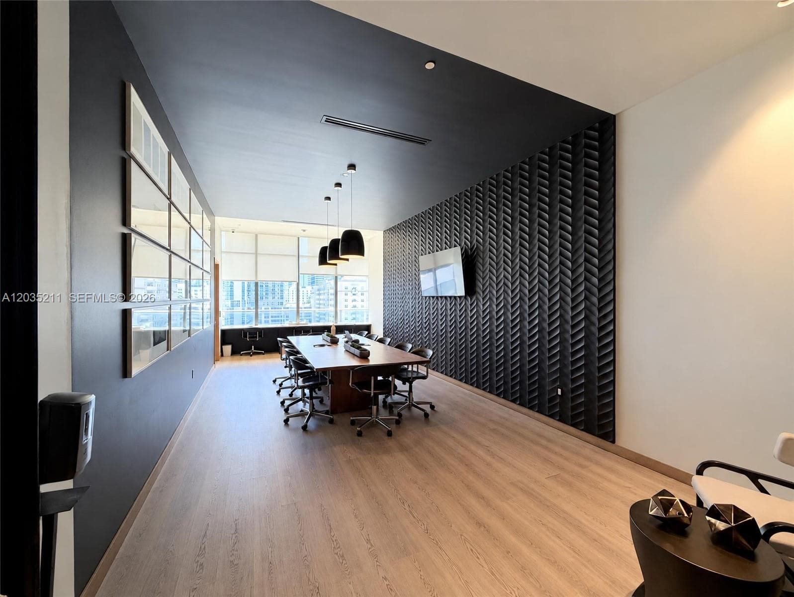 Conference room featuring wood-finish flooring, a decorative chevron-patterned accent wall, floor-to-ceiling windows, and three pendant light fixtures