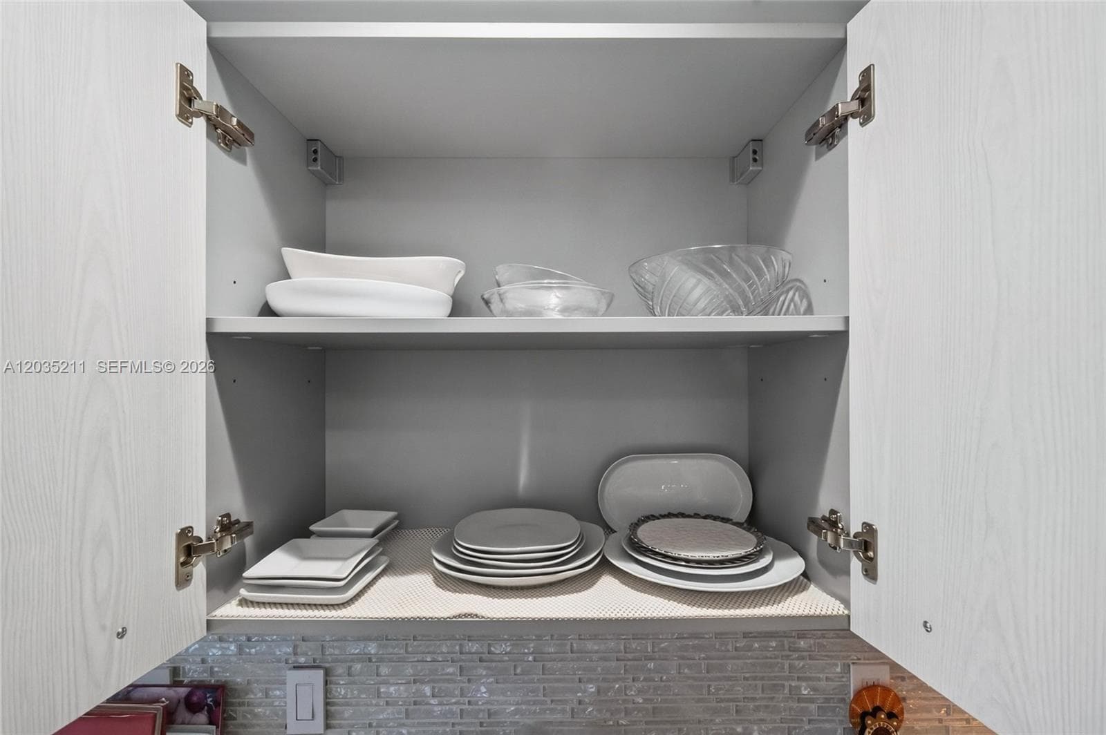 Cabinetry featuring light wood-grain finish doors, adjustable interior shelving, and soft-close hinges