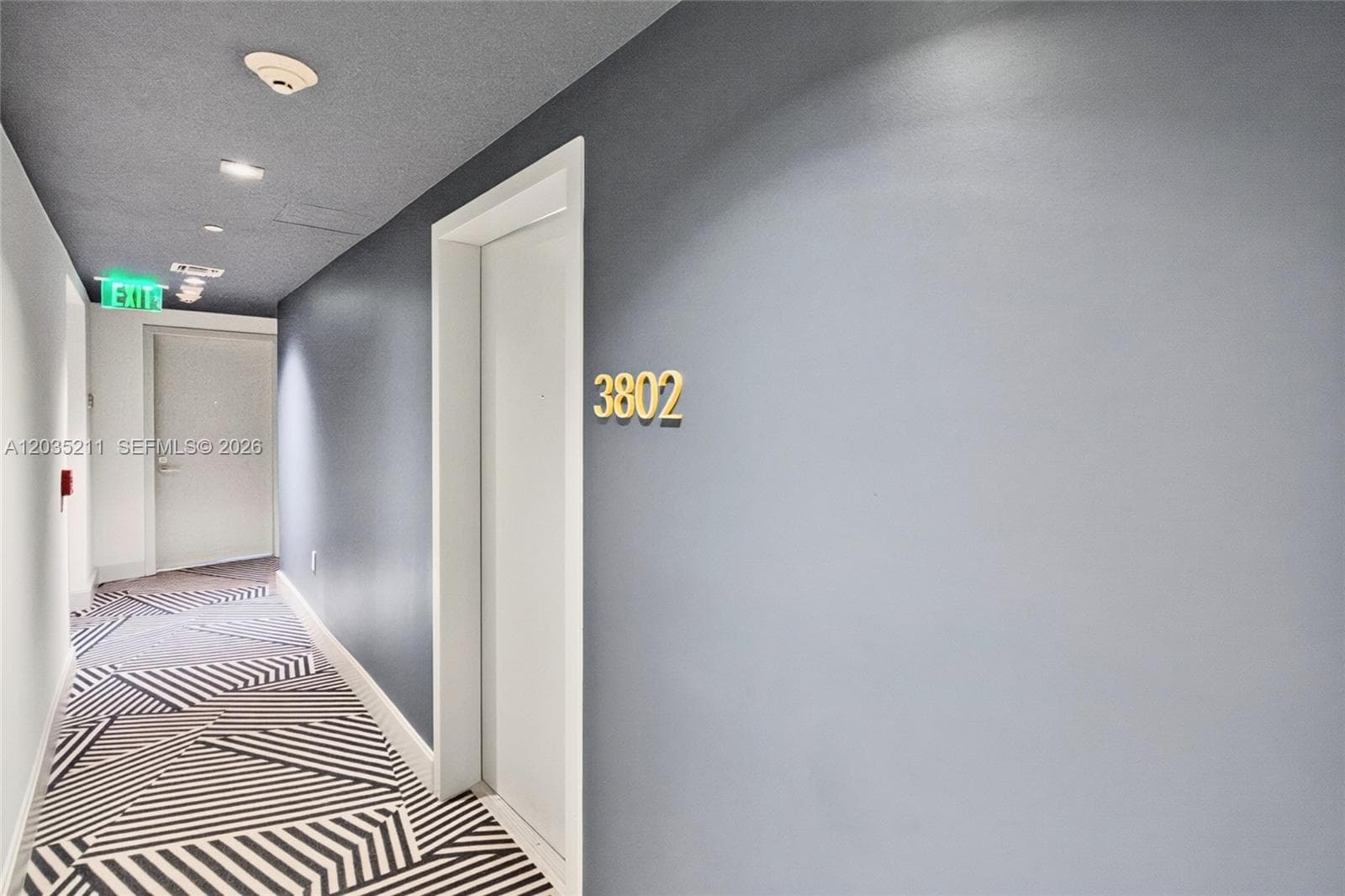 Interior hallway featuring geometric patterned carpet, recessed lighting, and painted walls