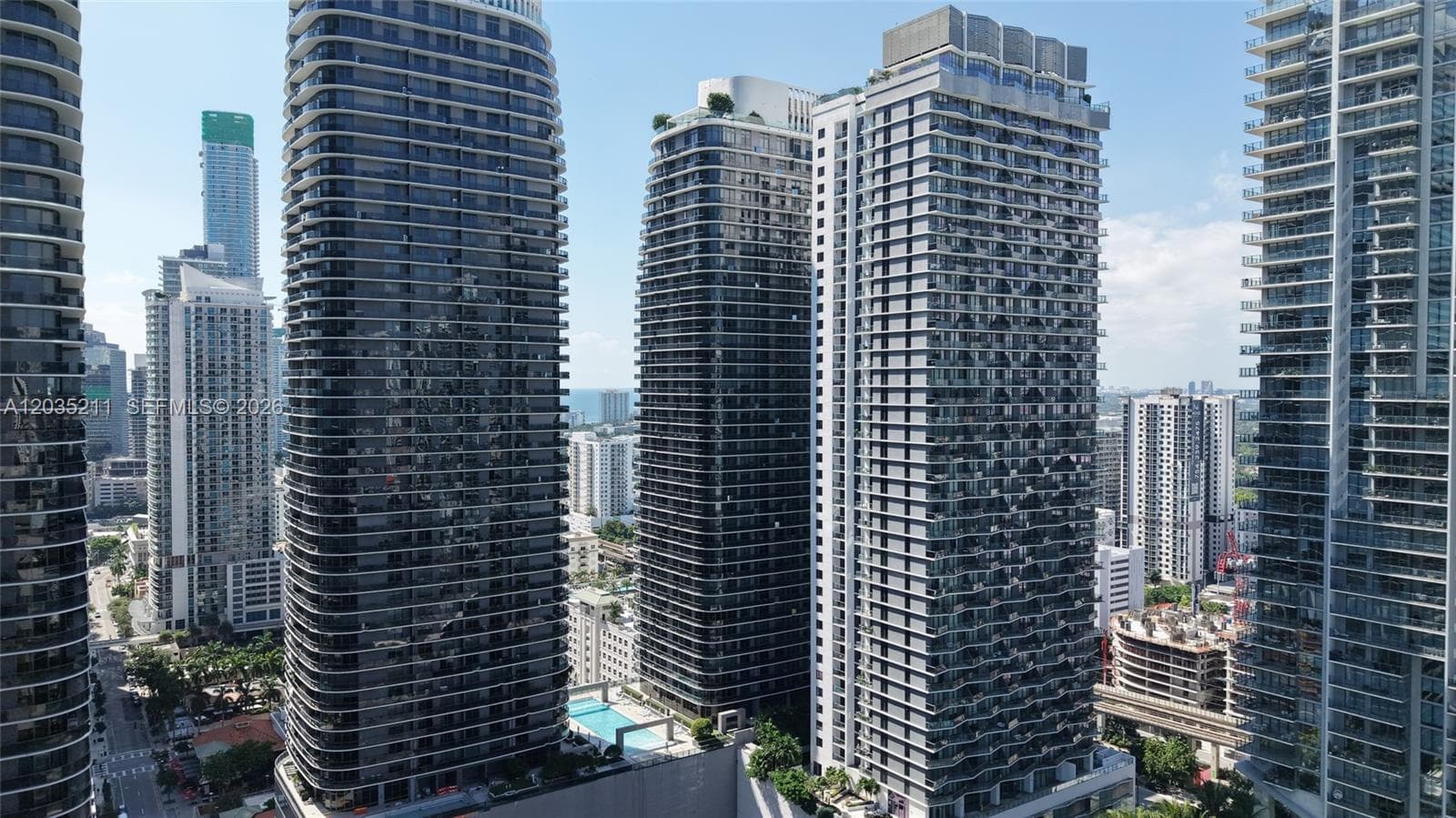 High-rise glass facade towers featuring floor-to-ceiling windows, private balconies, and an outdoor swimming pool