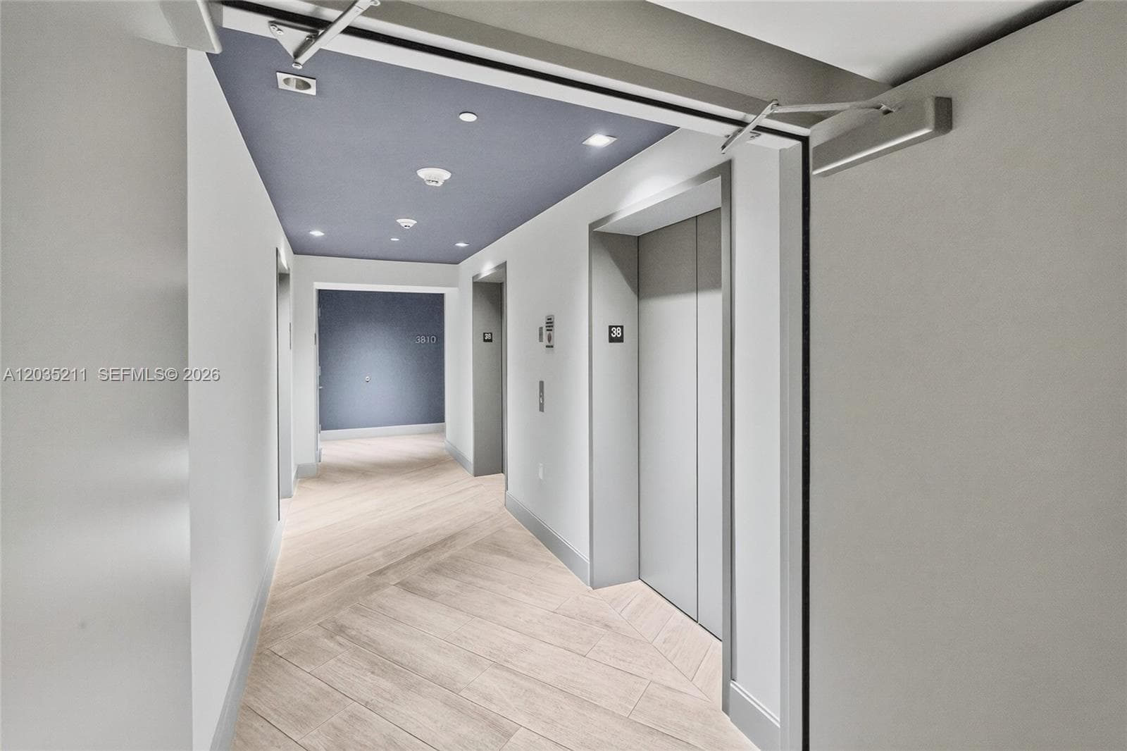 Hallway featuring herringbone-patterned flooring, recessed lighting, and a dual-tone ceiling design with colored acoustic panels