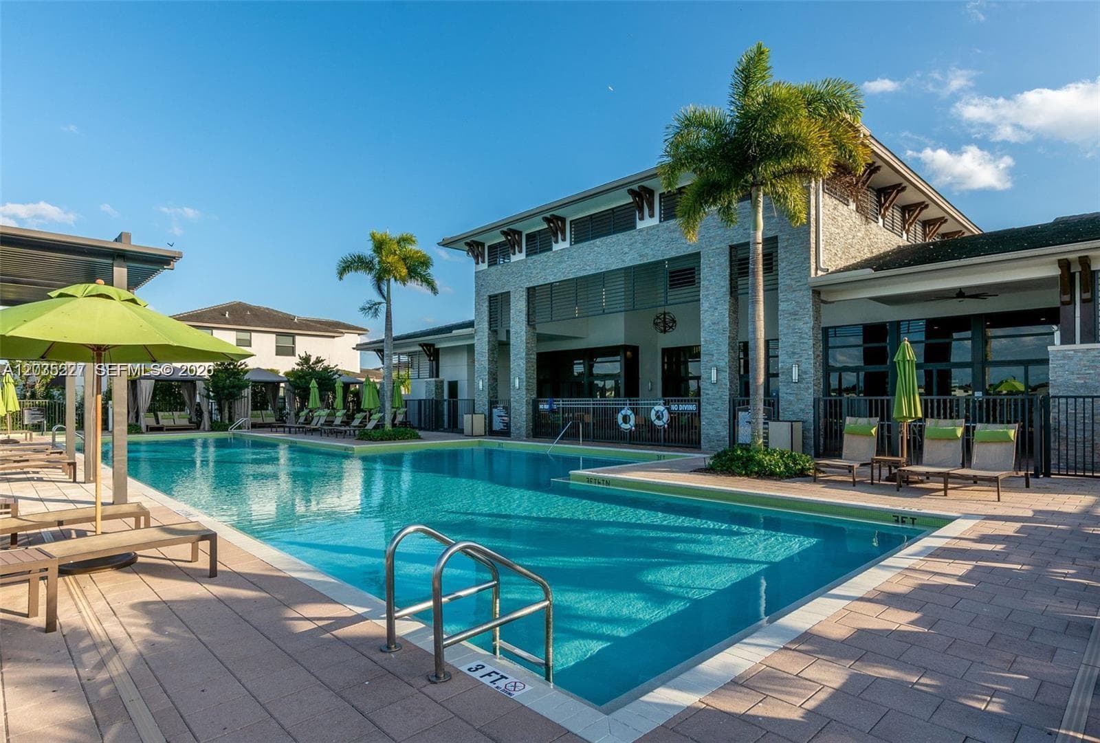 Stunning resort-style pool overlooking serene lake views, framed by swaying palm trees and a charming wood pergola. Lounge seating and a sun-drenched deck create the perfect waterfront escape for residents.