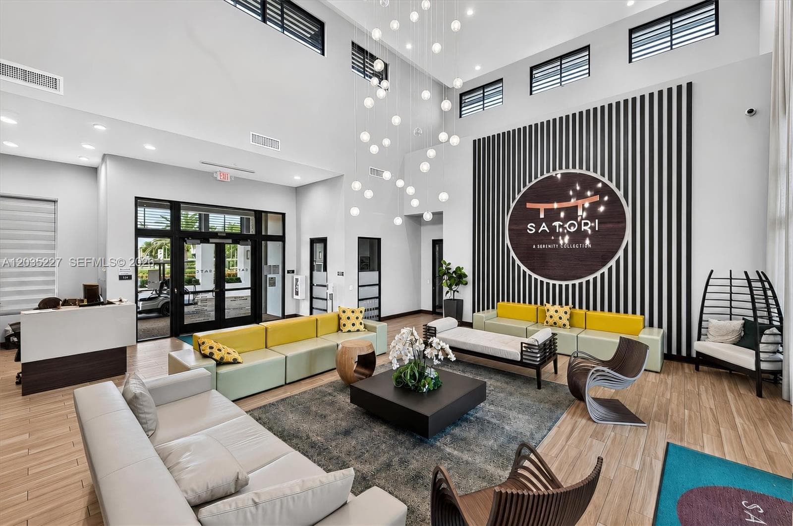 Striking double-height lobby with a dramatic bubble chandelier and bold designer furnishings in citrus tones. A statement signature wall and curated mix of textures create an upscale, hotel-inspired first impression.