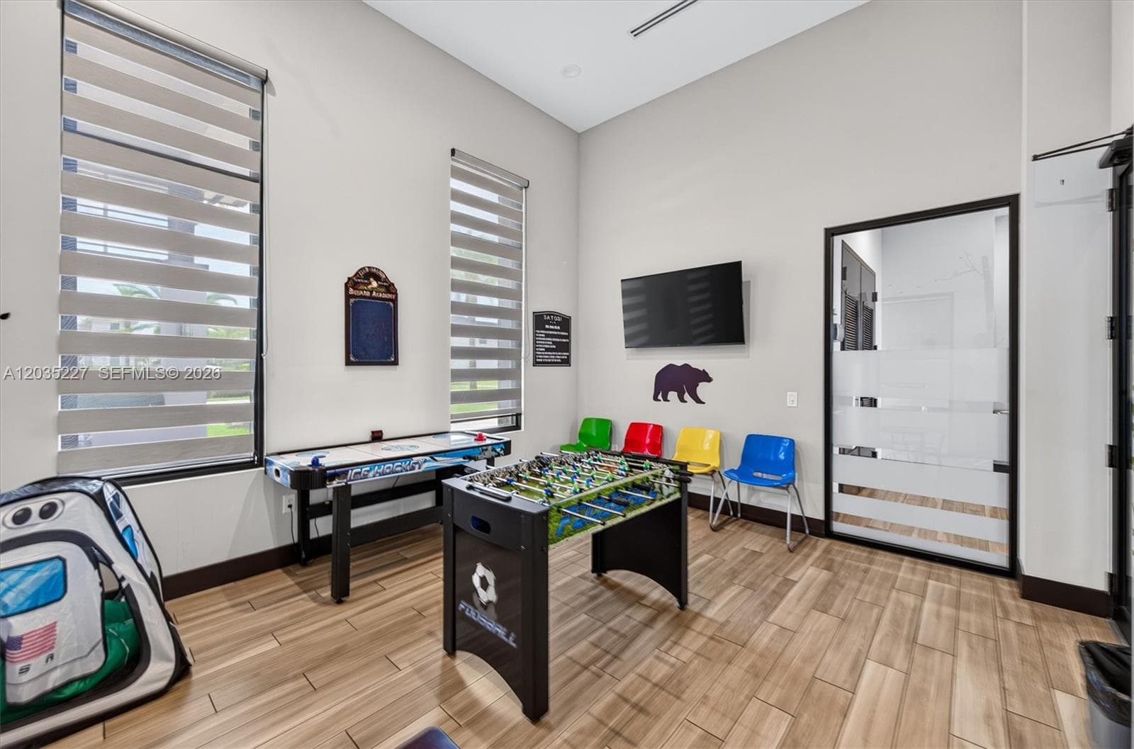 Fun-filled kids' game room complete with foosball, air hockey, and a wall-mounted TV for endless entertainment. Bright natural light and durable flooring make this a playful, family-friendly community amenity.