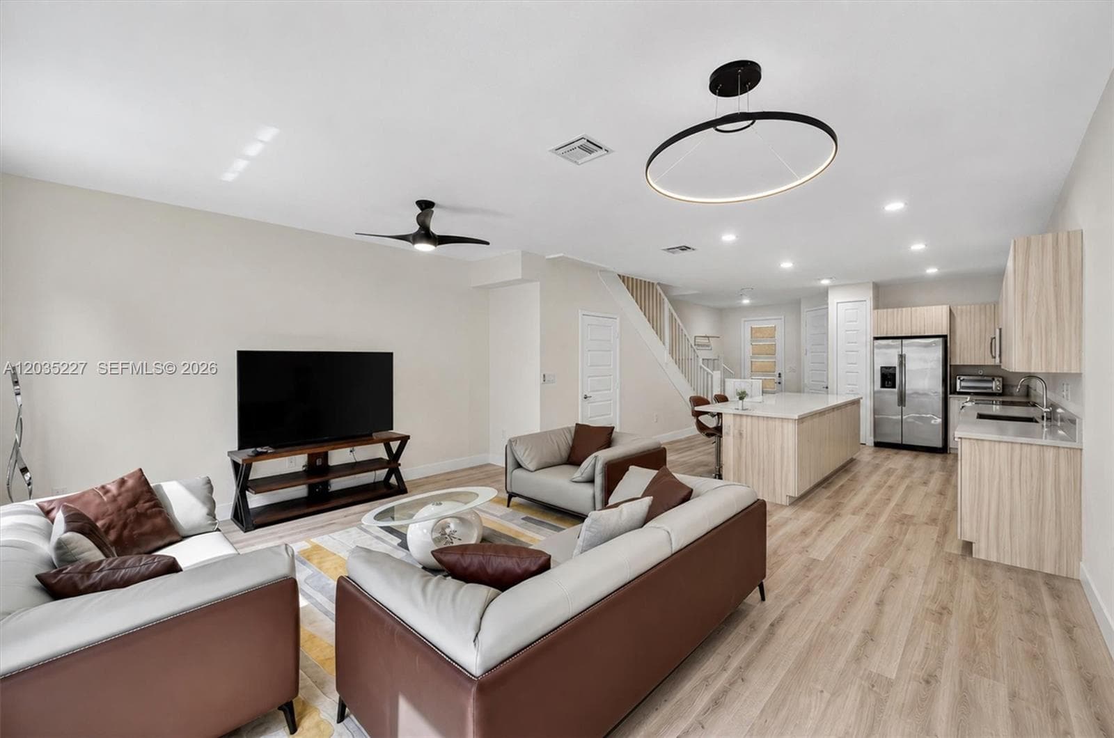 Open-concept living space seamlessly flowing into the gourmet kitchen, perfect for entertaining. Designer lighting and wide-plank flooring tie the modern aesthetic together throughout the spacious and sleek downstairs.