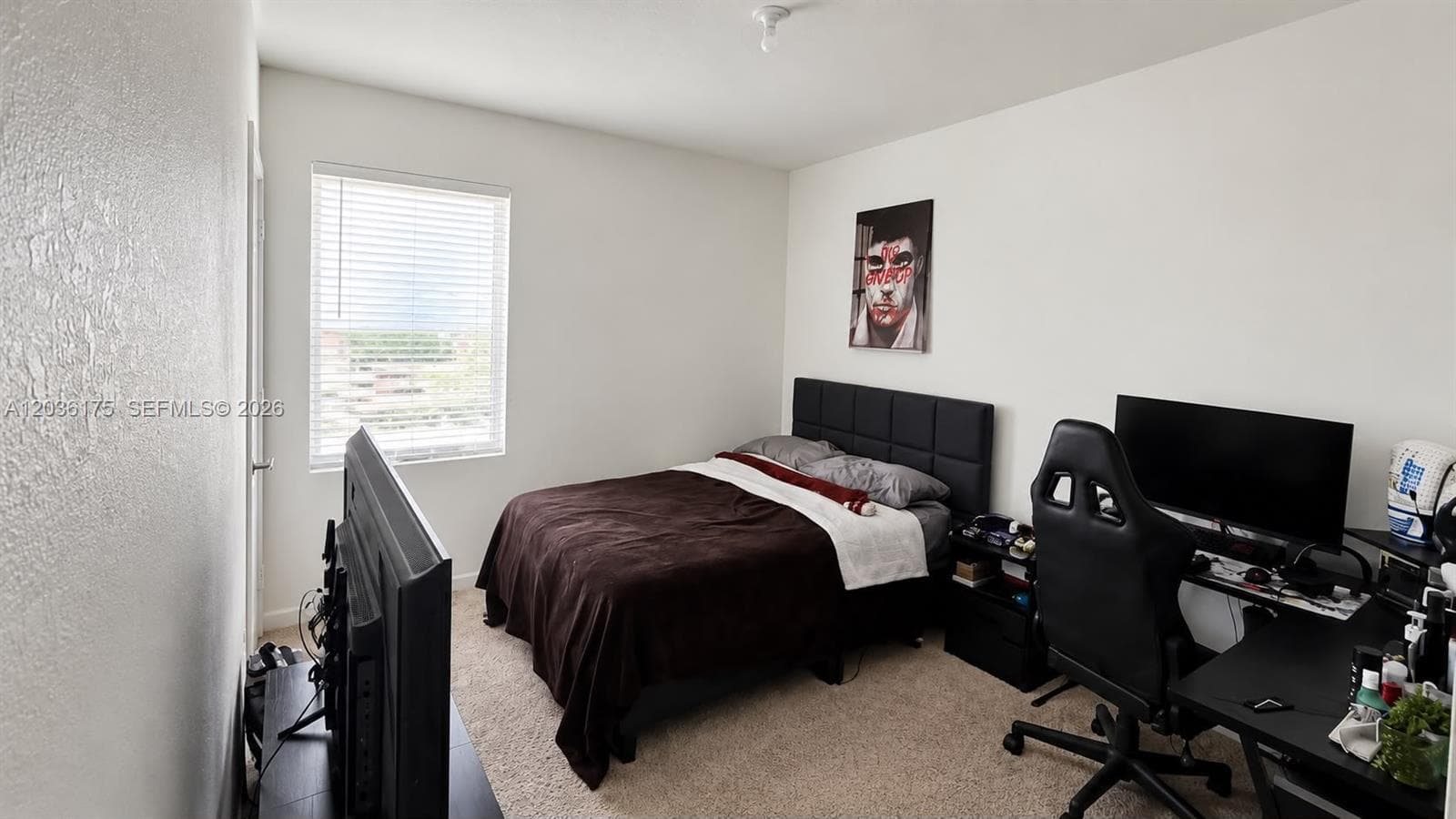 Neutral-toned bedroom featuring carpeted flooring and a window with horizontal blinds