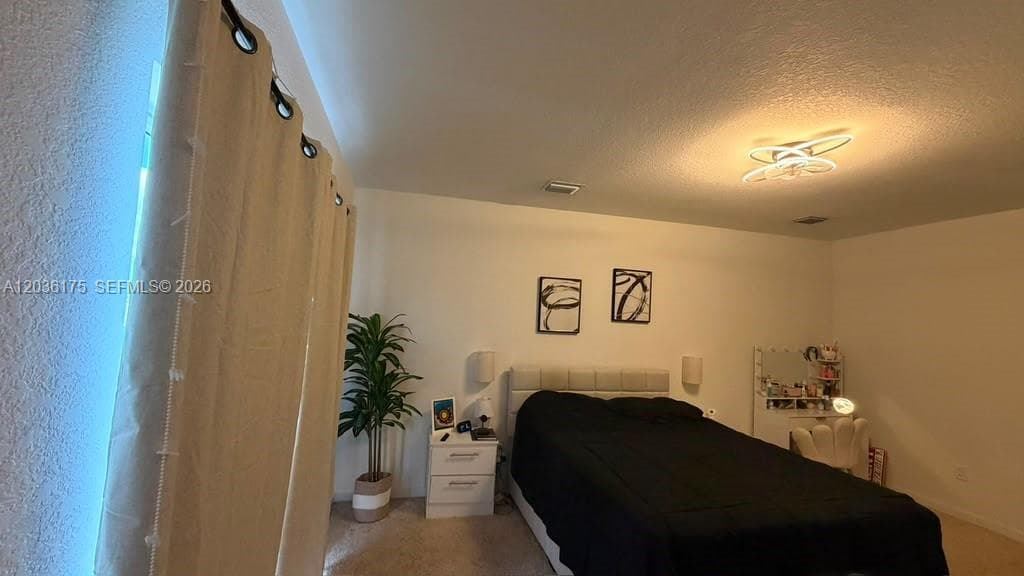Interior space featuring textured walls, neutral carpeting, and a contemporary multi-ring flush mount light fixture