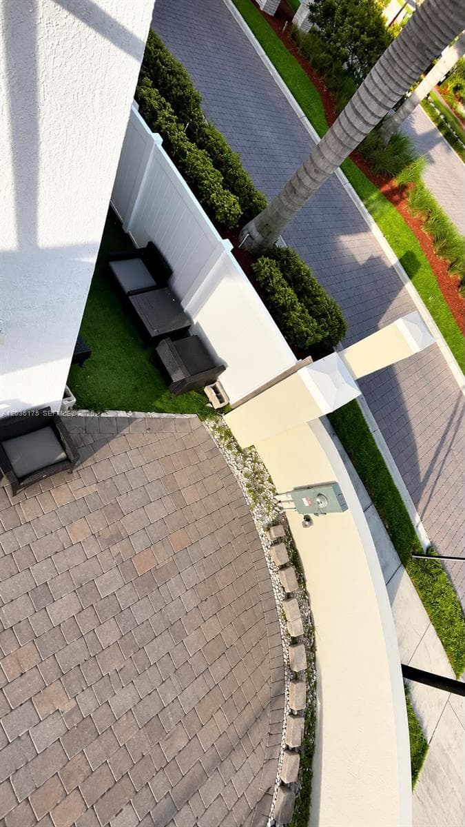 Paver patio with curved stone-finished border, privacy vinyl fencing, and maintenance-free synthetic turf area