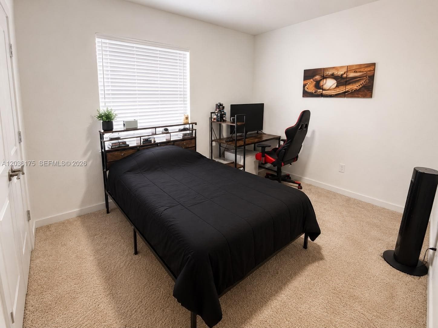 Neutral-toned interior room featuring wall-to-wall carpeting, an expansive window with integrated horizontal blinds, and a paneled interior door with metal hardware