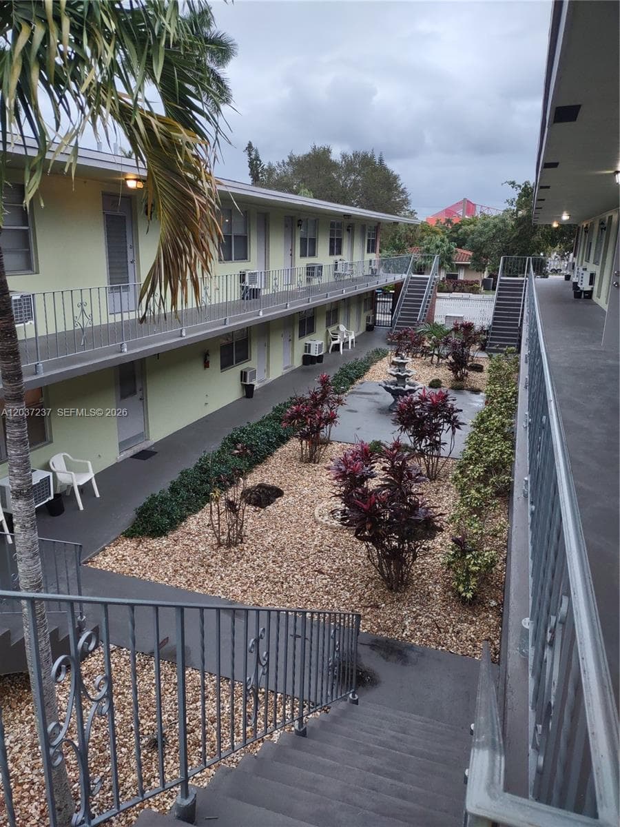 Courtyard featuring a decorative water fountain, gravel landscaping, manicured shrubbery, and metal railings