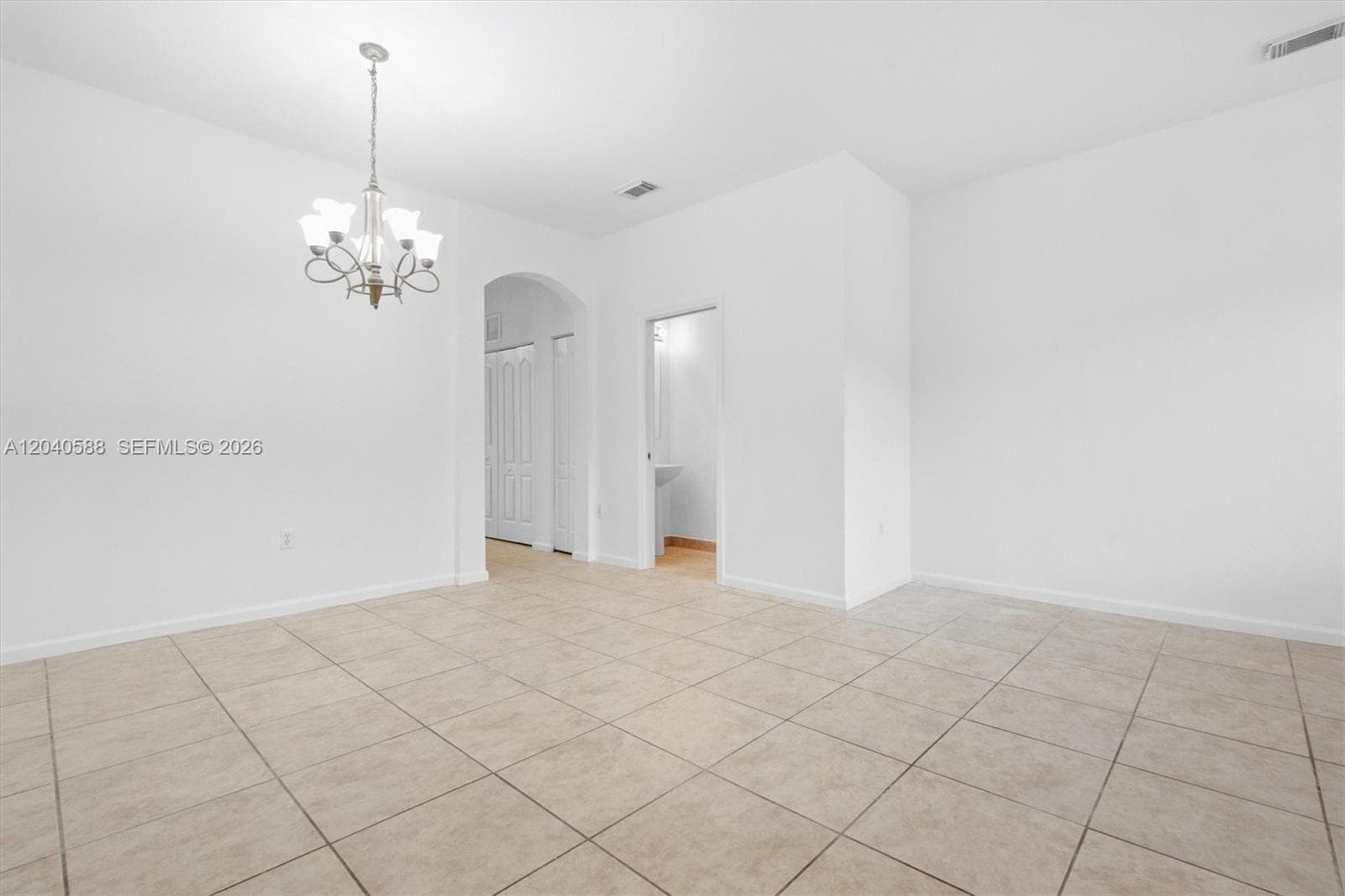 Tile flooring, arched doorway, ceiling-mounted light fixture, white walls, built-in pedestal sink