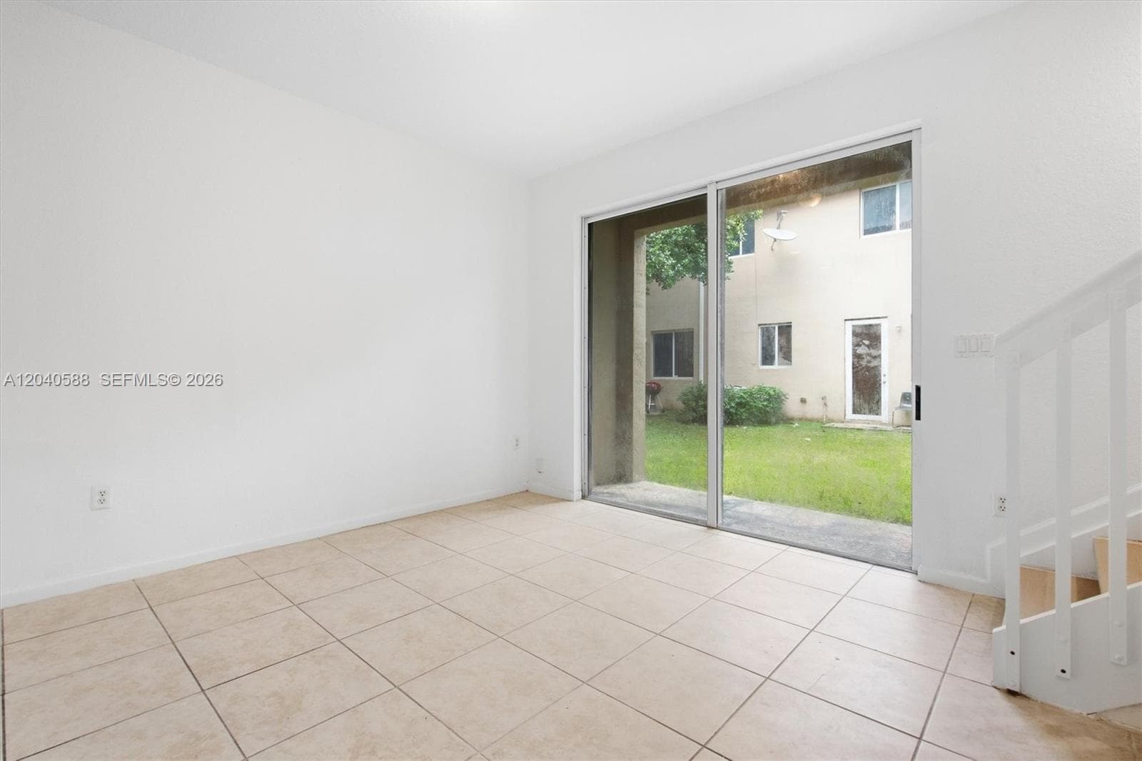 Neutral-toned tile flooring, white painted walls, and a sliding glass door providing outdoor access