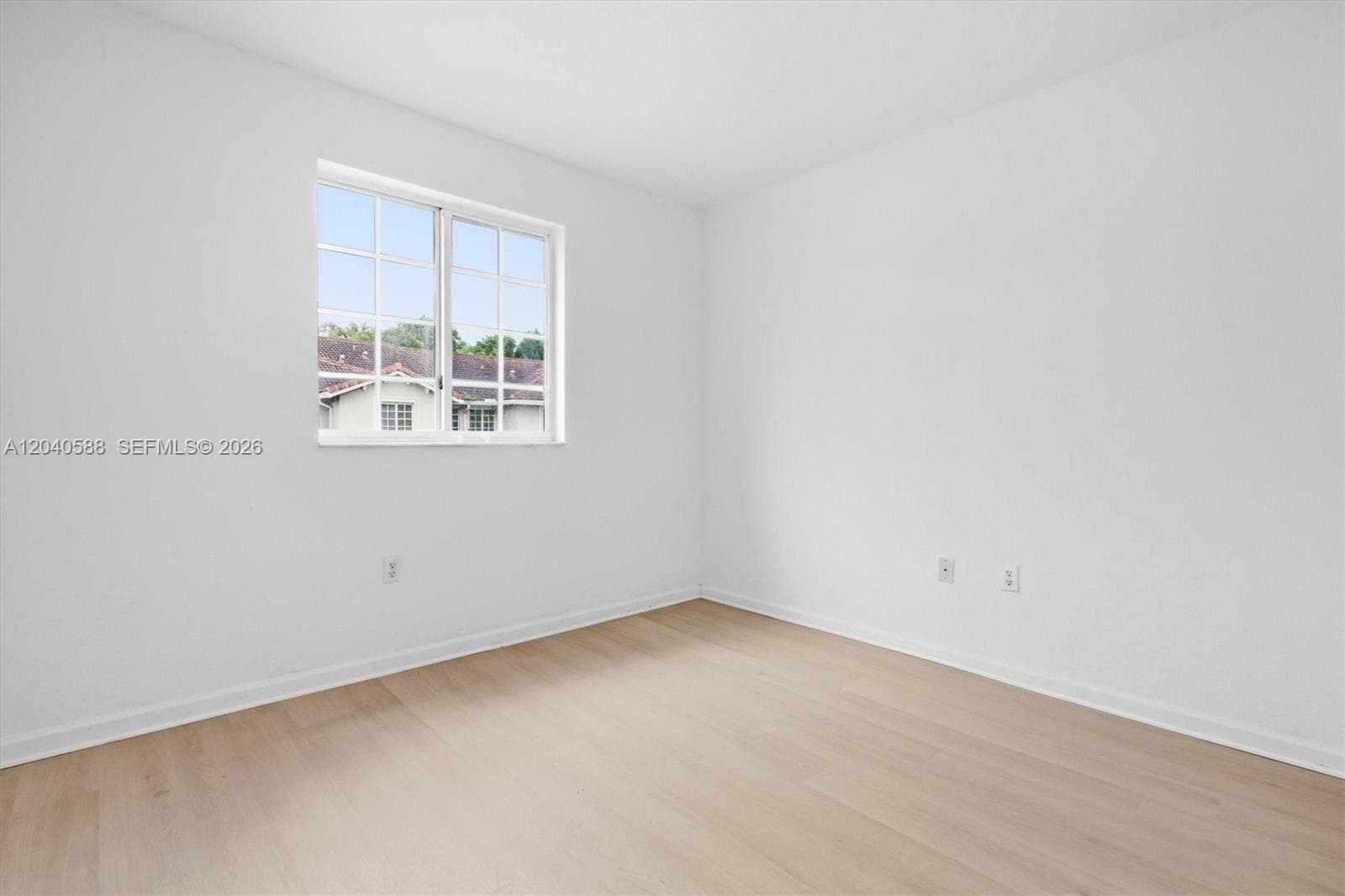 Light wood-finish flooring with white walls and trim, featuring a multi-pane window