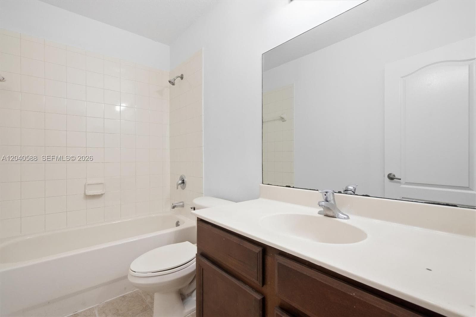Spacious bathroom featuring a wood-finish vanity with dual sink configuration, white countertop, and large framed mirror