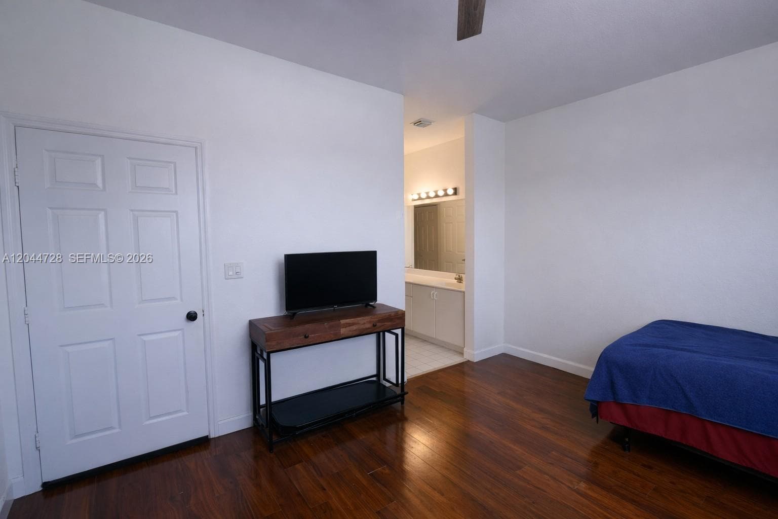 1st Mater Bedroom with laminated flooring, simple layout, and direct access to a bright vanity area. Functional space with neutral finishes.