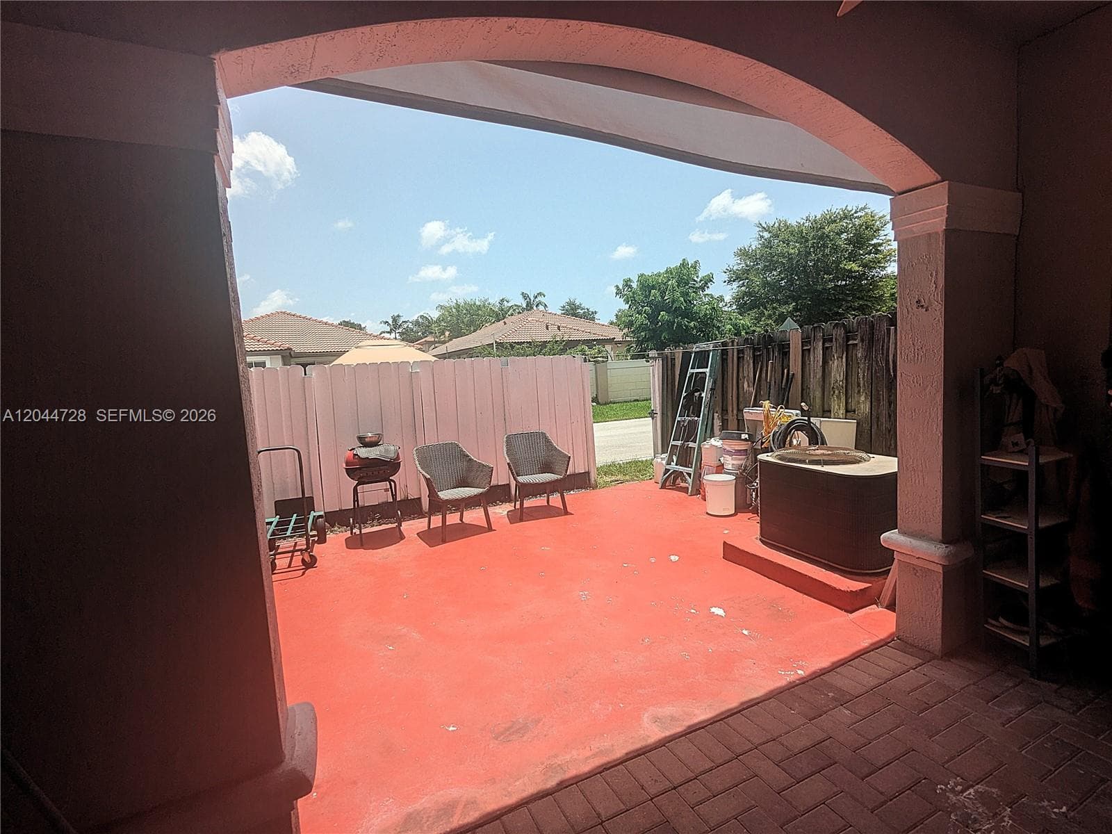 Private patio with covered area, concrete flooring, and fenced enclosure. Functional outdoor space with seating and room for additional storage.