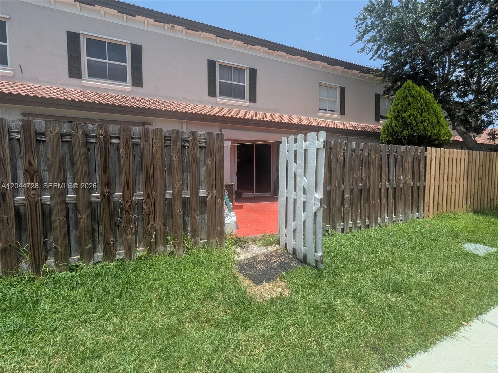 Fenced backyard with red concrete patio and direct access to the home. Clean outdoor space with open lawn and private enclosure.