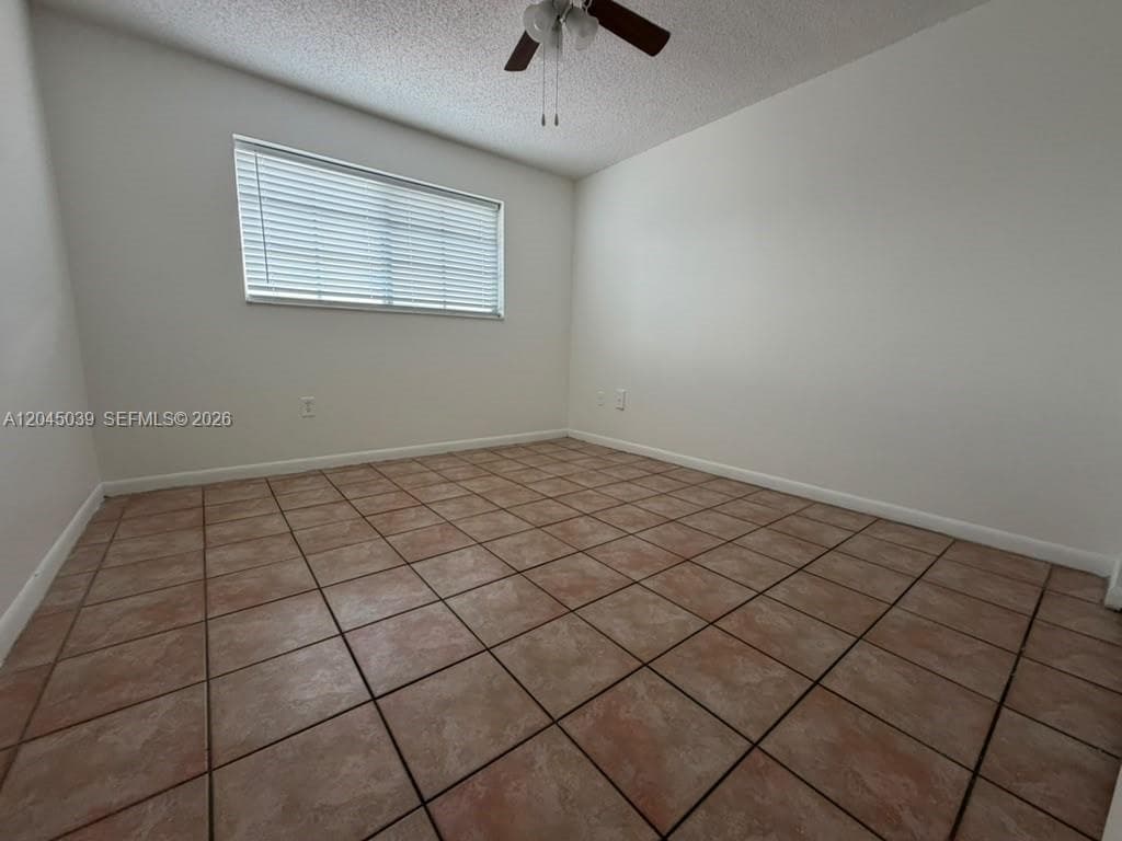 Room featuring ceramic tile flooring, neutral wall paint, and a ceiling fan with integrated lighting