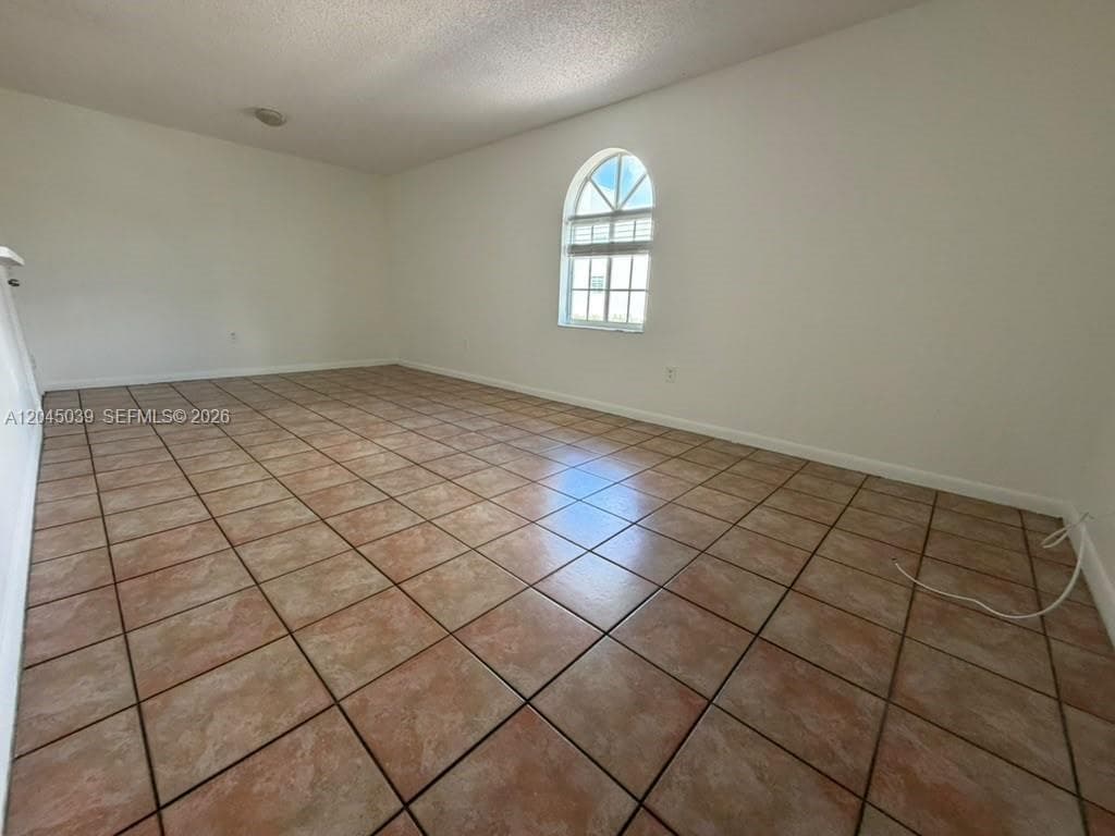 Interior space featuring ceramic tile flooring, neutral wall finishes, and an arched window with integrated muntins