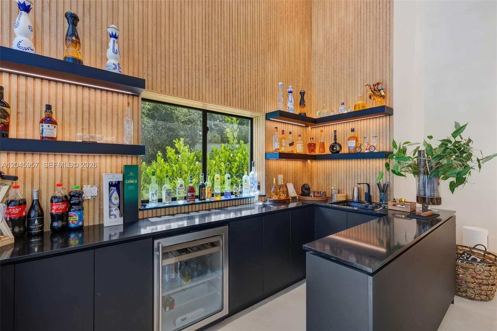 A custom-built entertaining bar with integrated refrigeration, designer shelving, and warm architectural detailing creates the perfect space to host family and friends