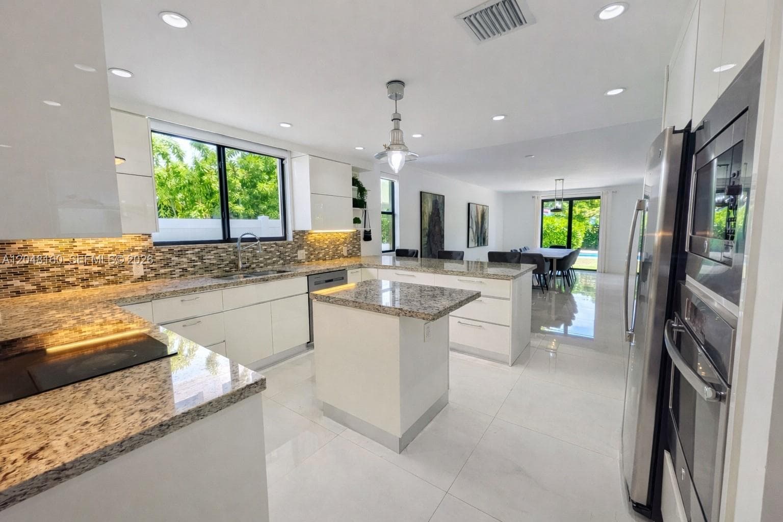 elegant modern kitchen with ample counter space, custom cabinetry, glass cooktop and stainless steel appliances.