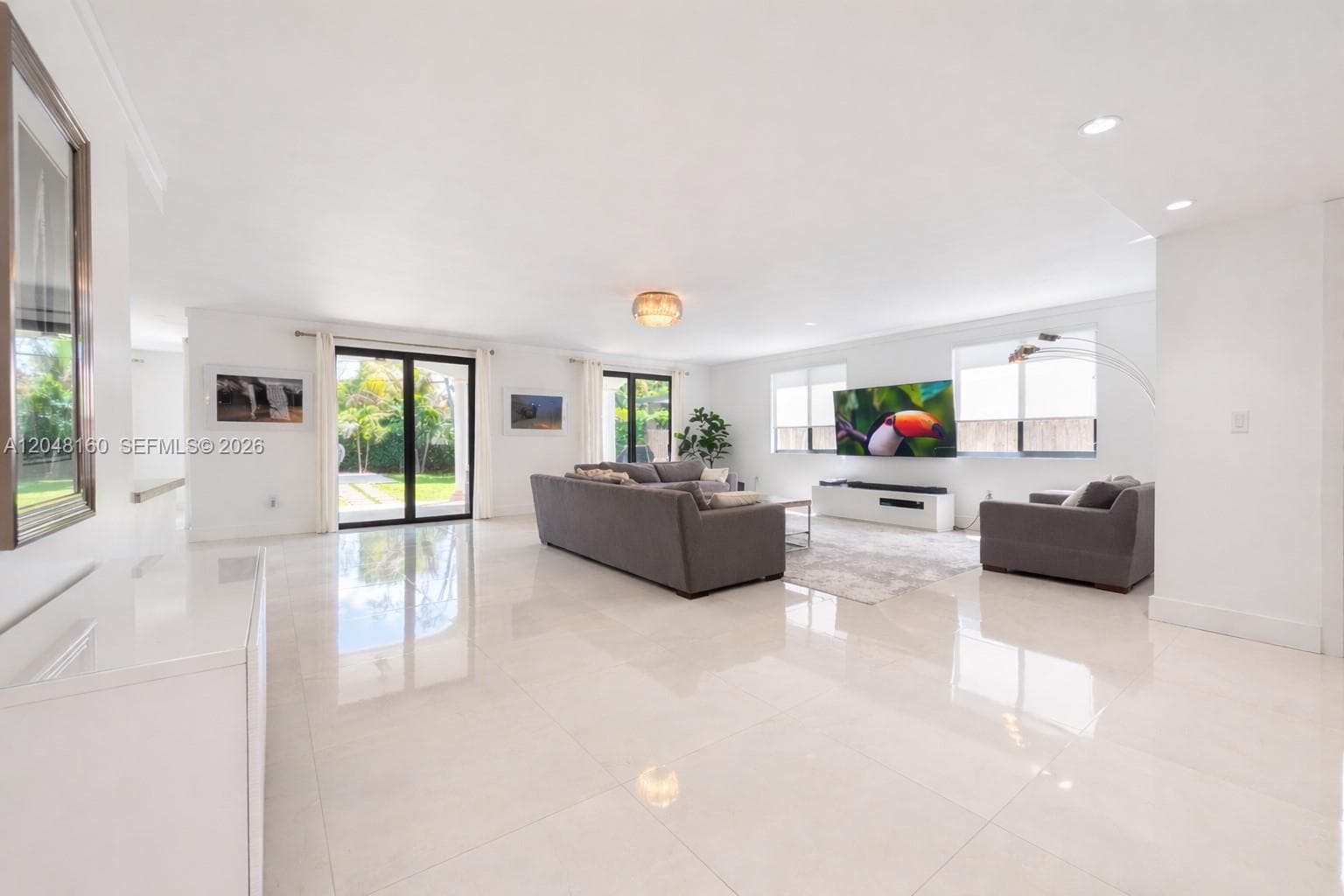 spacious open 1st floor living room, with floor-to-ceiling glass doors leading to back yard terrace and pool.
