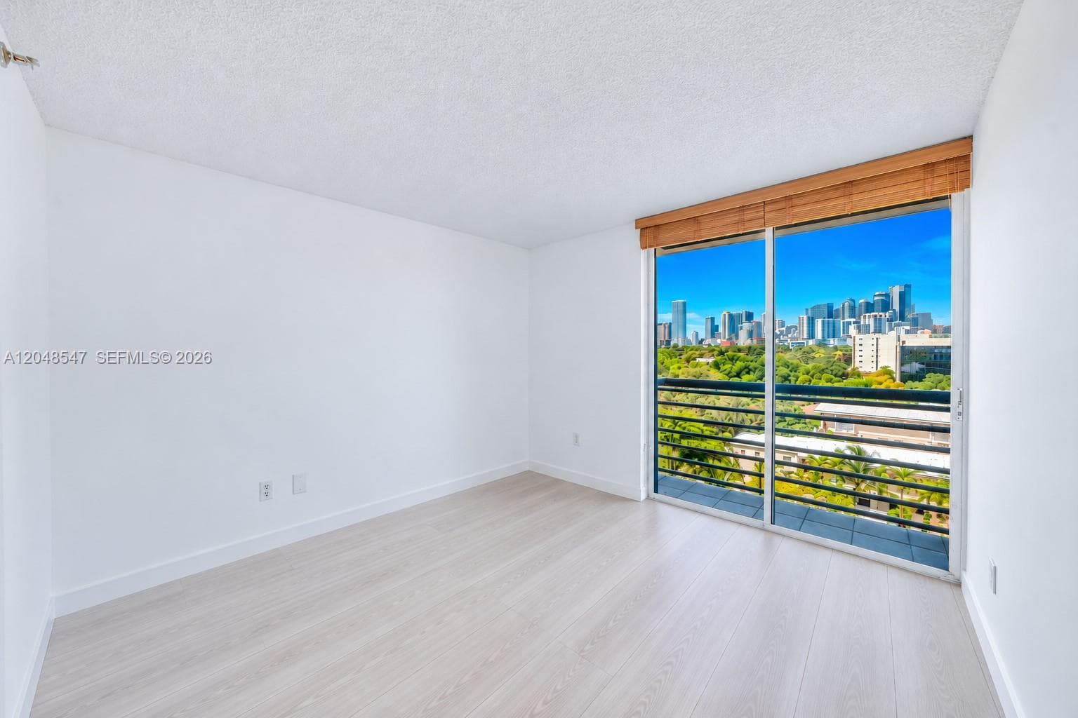 Bright interior featuring wood-finish flooring, sliding glass balcony door, and cityscape scenery