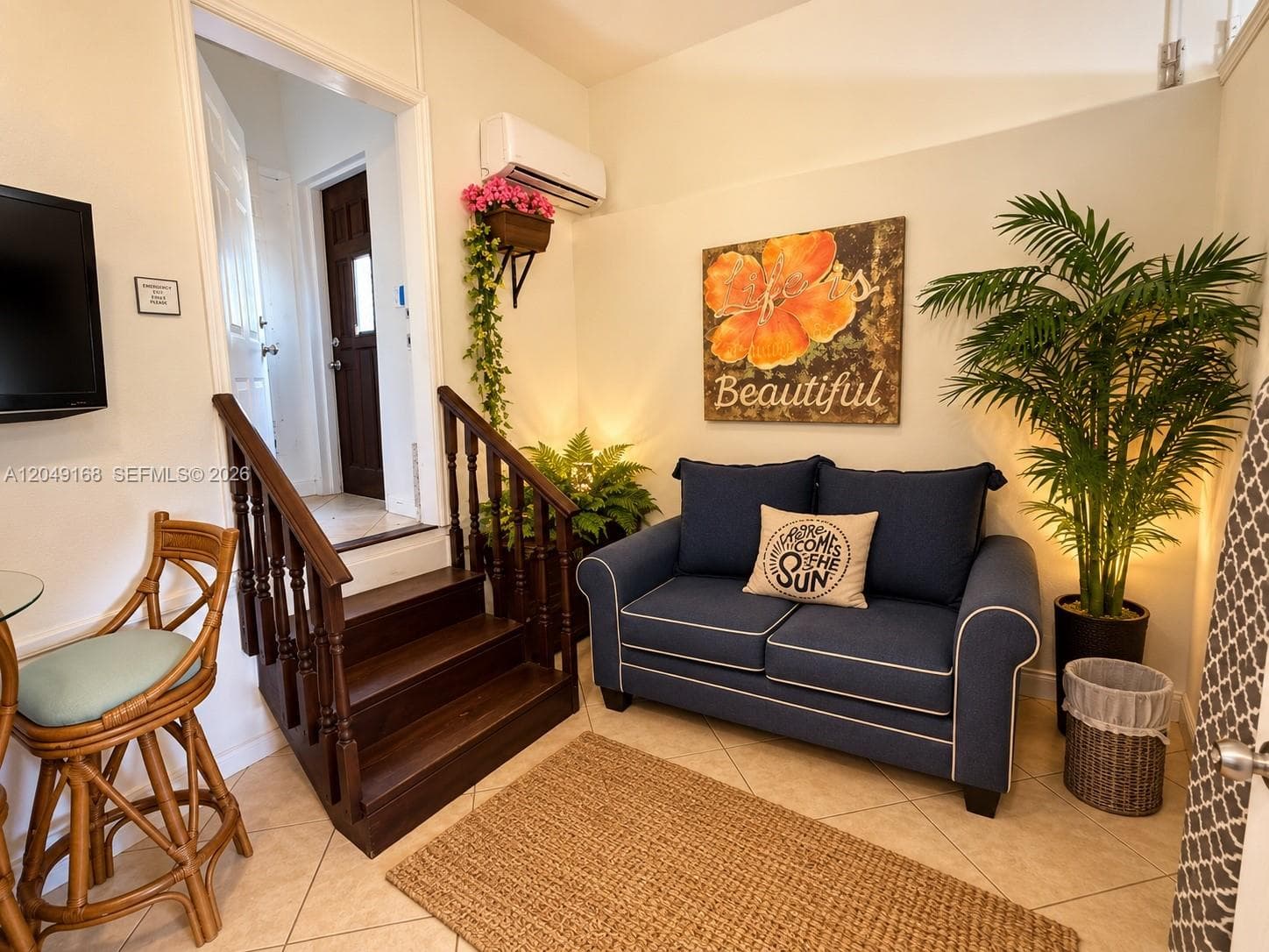 Tile flooring, wooden staircase with detailed balusters, and wall-mounted climate control unit