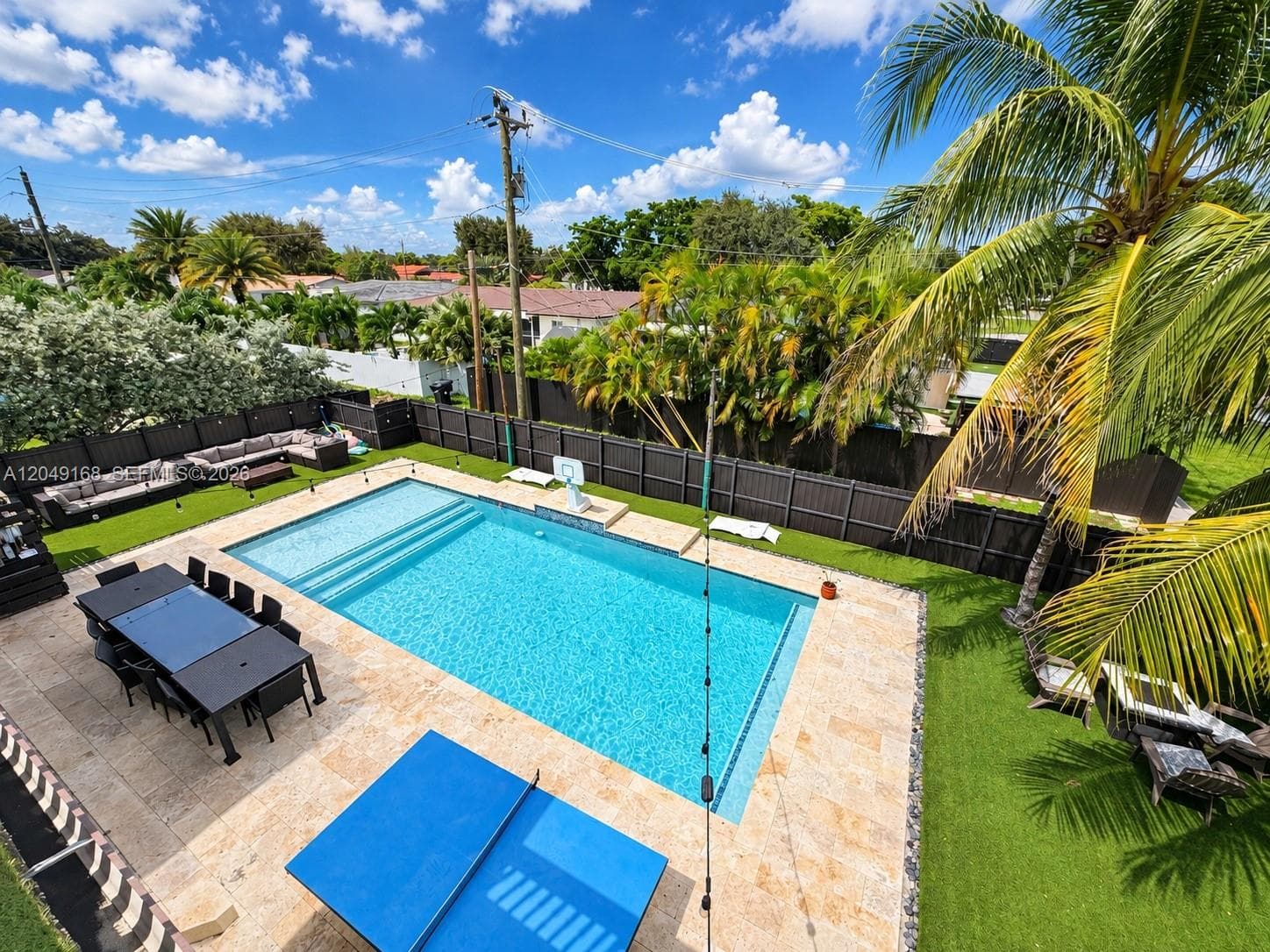 Private outdoor area featuring an in-ground swimming pool, stone paver decking, artificial turf lawn, and perimeter privacy fencing