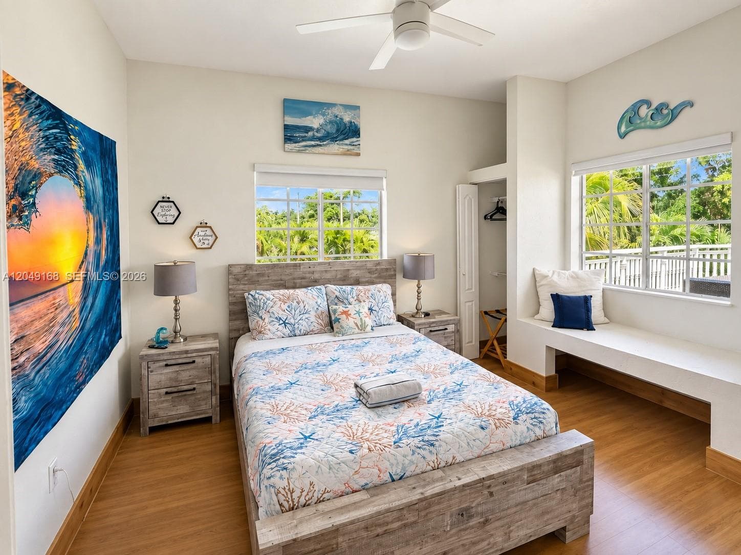 Room featuring wood-finish flooring, dual grid-pattern windows, a built-in window seat, and a ceiling fan