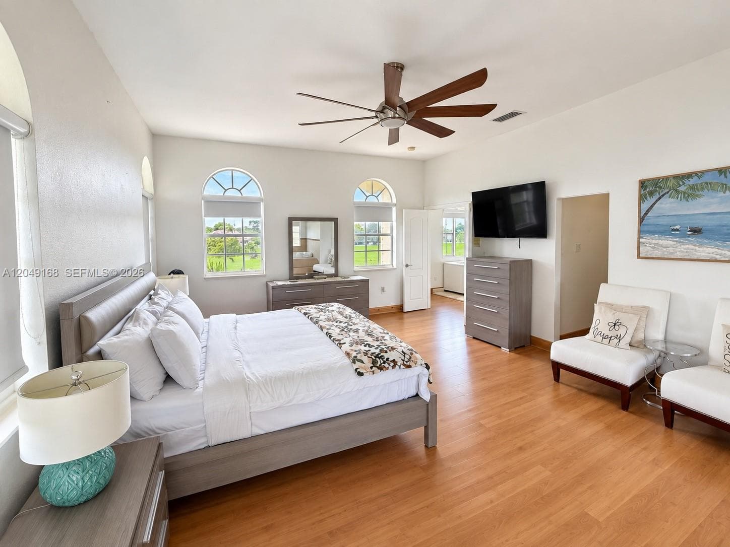 Spacious interior featuring wood-finish flooring, high ceilings with an integrated ceiling fan, and multiple arched windows