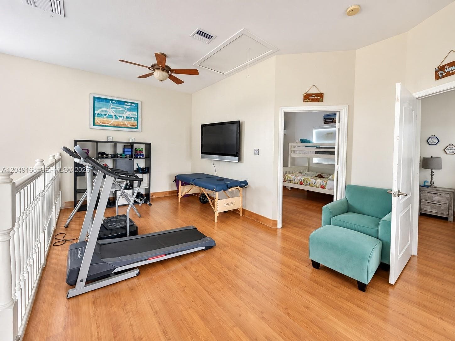 Wood-finish flooring, vaulted ceilings, ceiling fan, and white metal balustrade railing