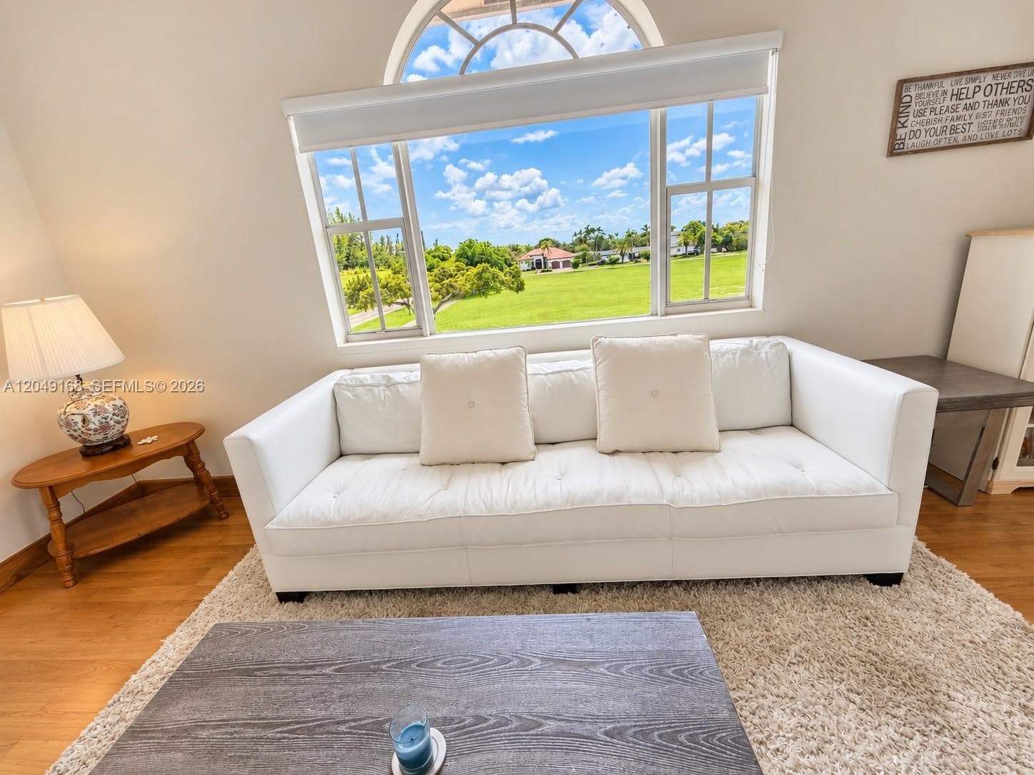 Expansive arched window with multi-pane configuration, wood-finish flooring, and natural lighting