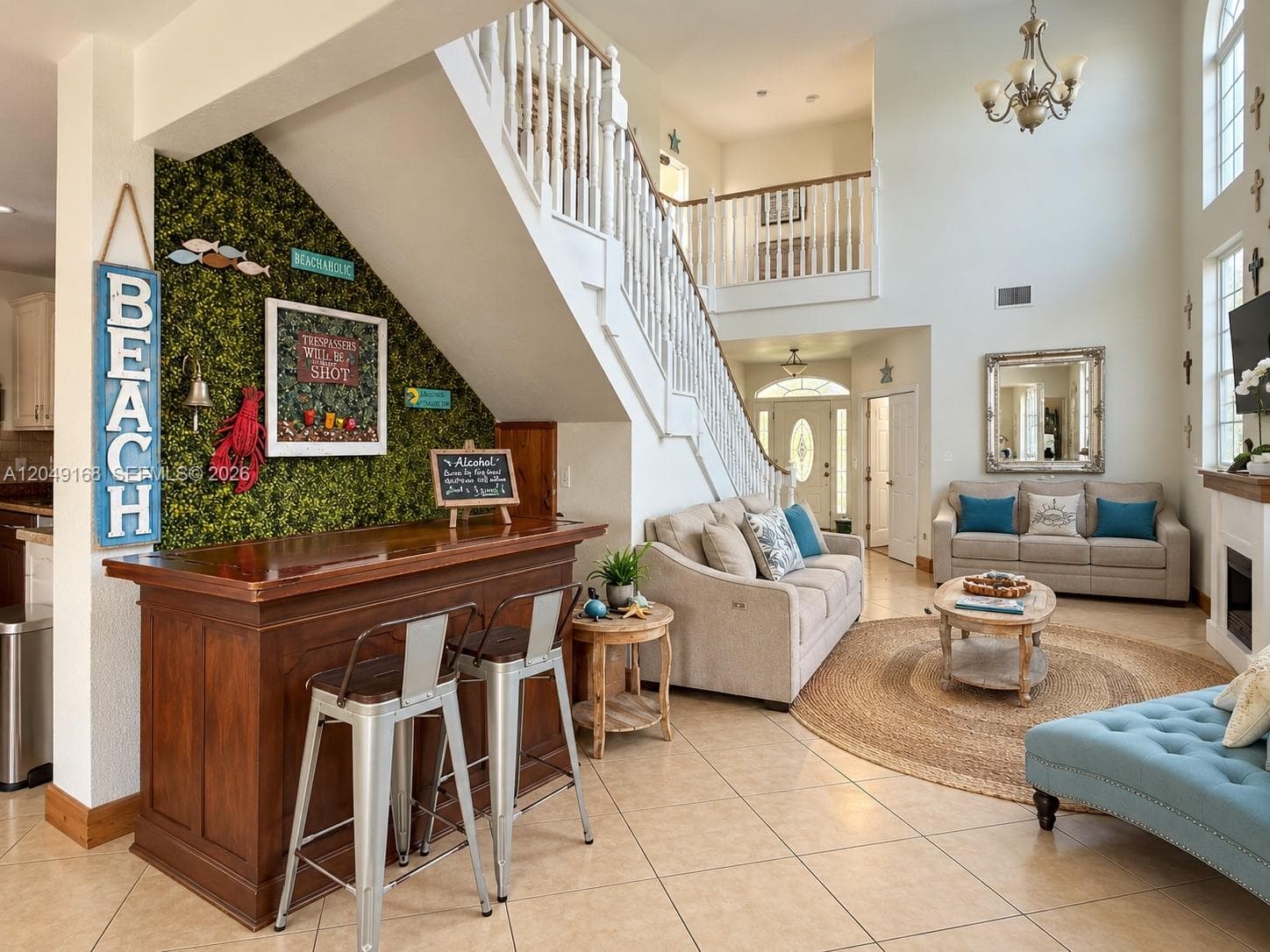 Two-story foyer featuring tile flooring, a built-in wood bar, a staircase with white balusters, a fireplace, and tall windows