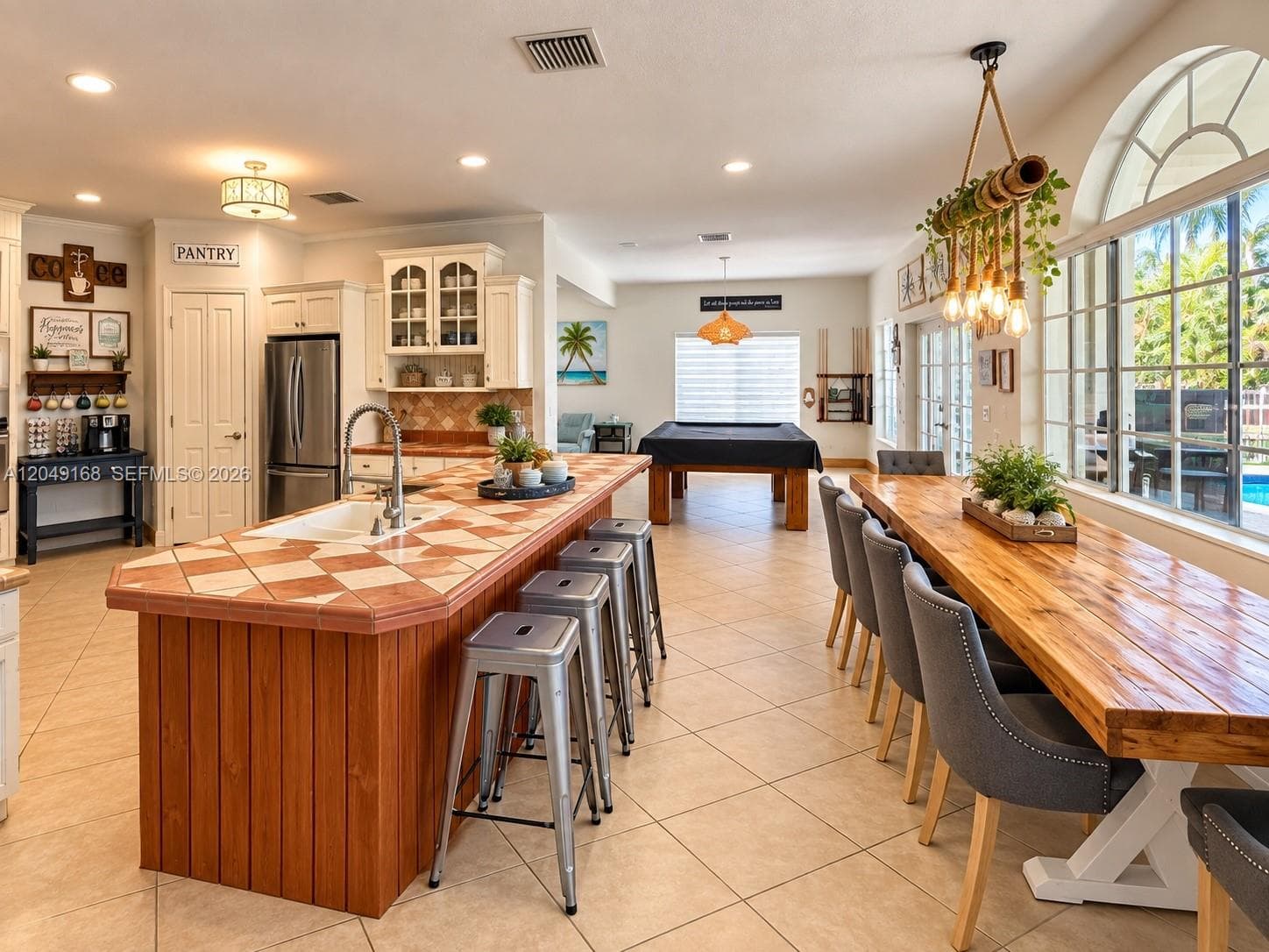 Kitchen featuring a center island with tile countertops, wood cabinetry, recessed lighting, and a multi-light chandelier