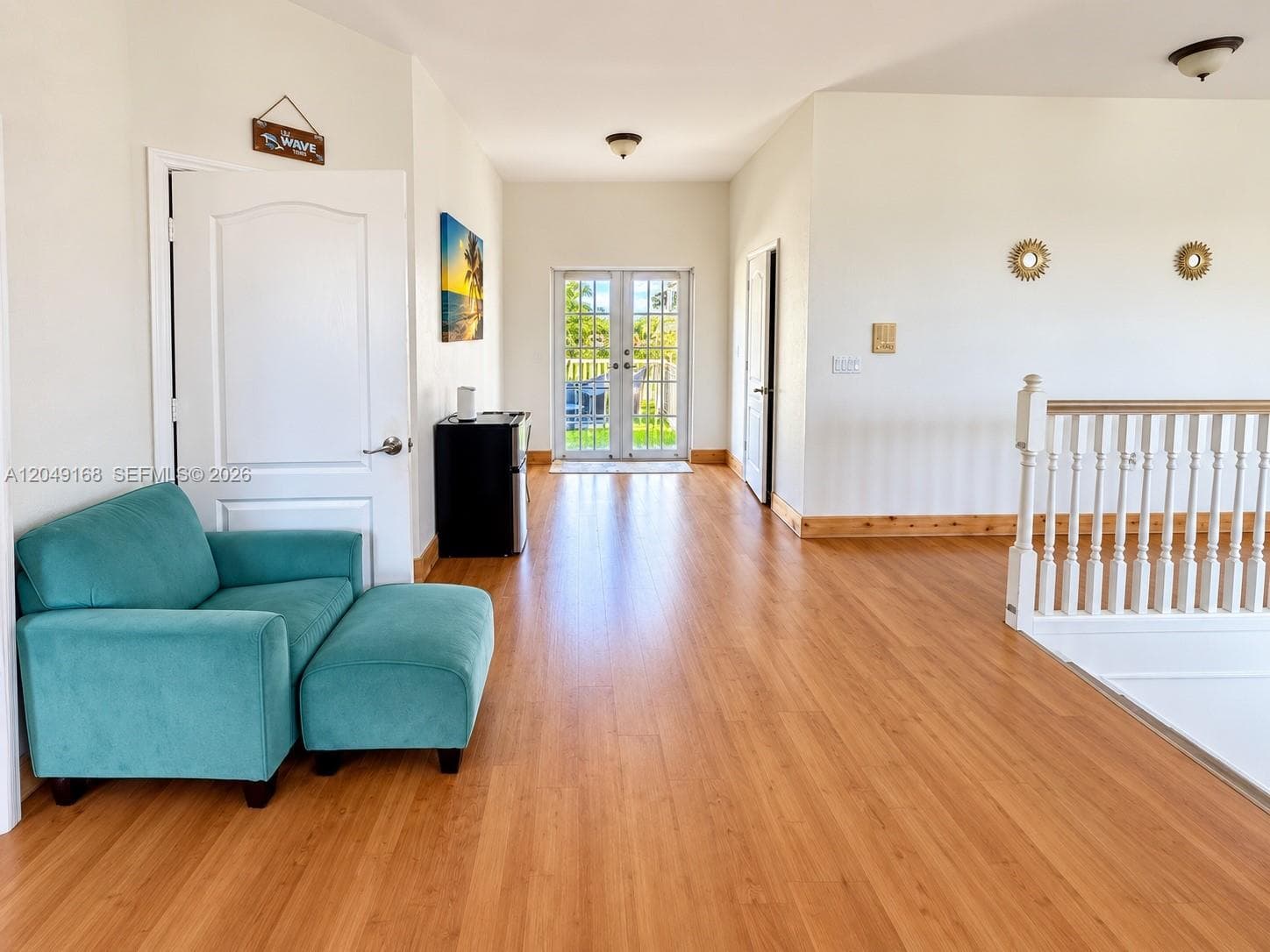 Wood-finish flooring, white paneled interior doors, wood-trimmed railing, and glass-paned double doors