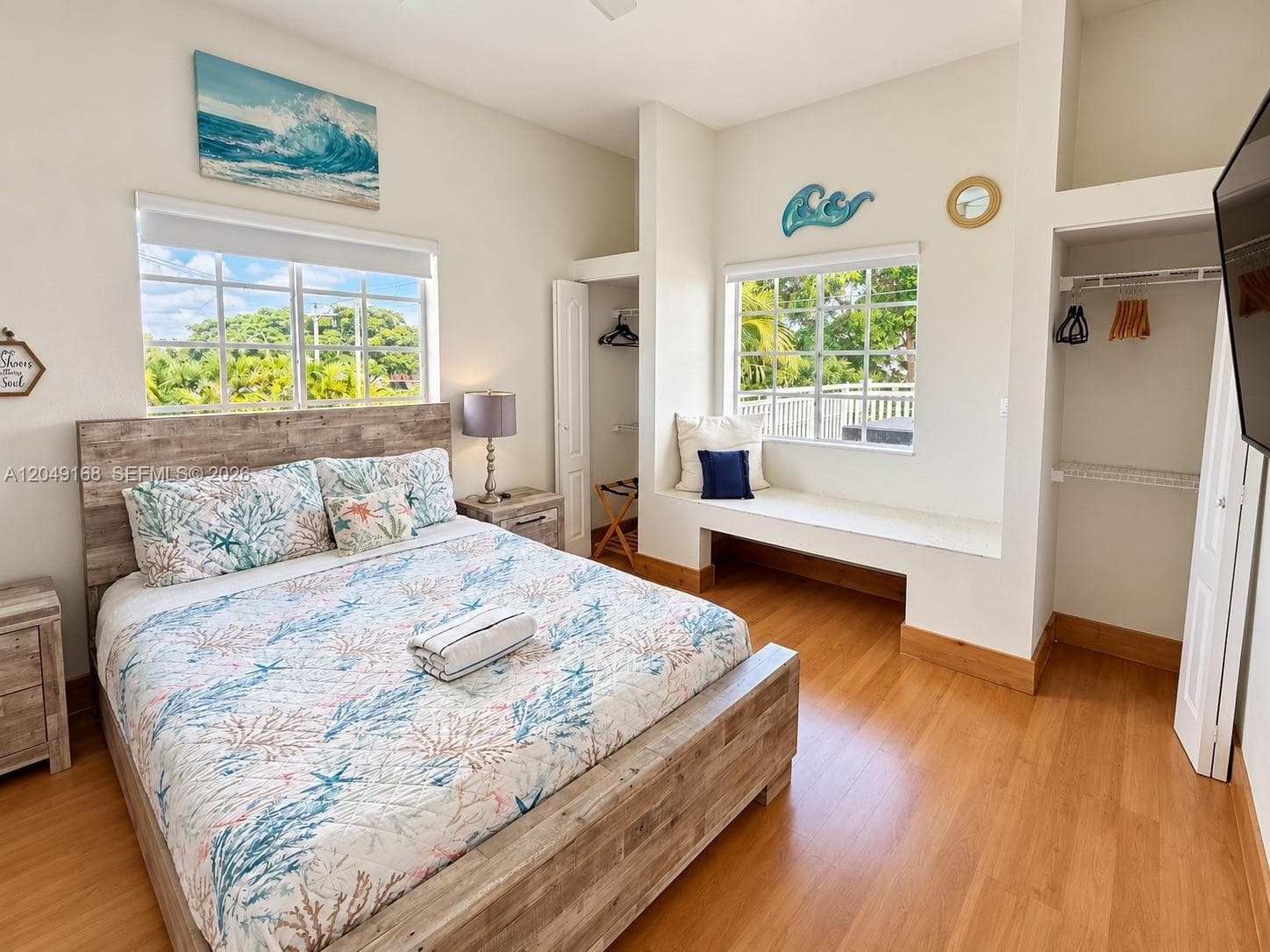 Bedroom featuring wood-finish flooring, built-in window seating, two grid-pane windows, and a recessed closet with wire shelving