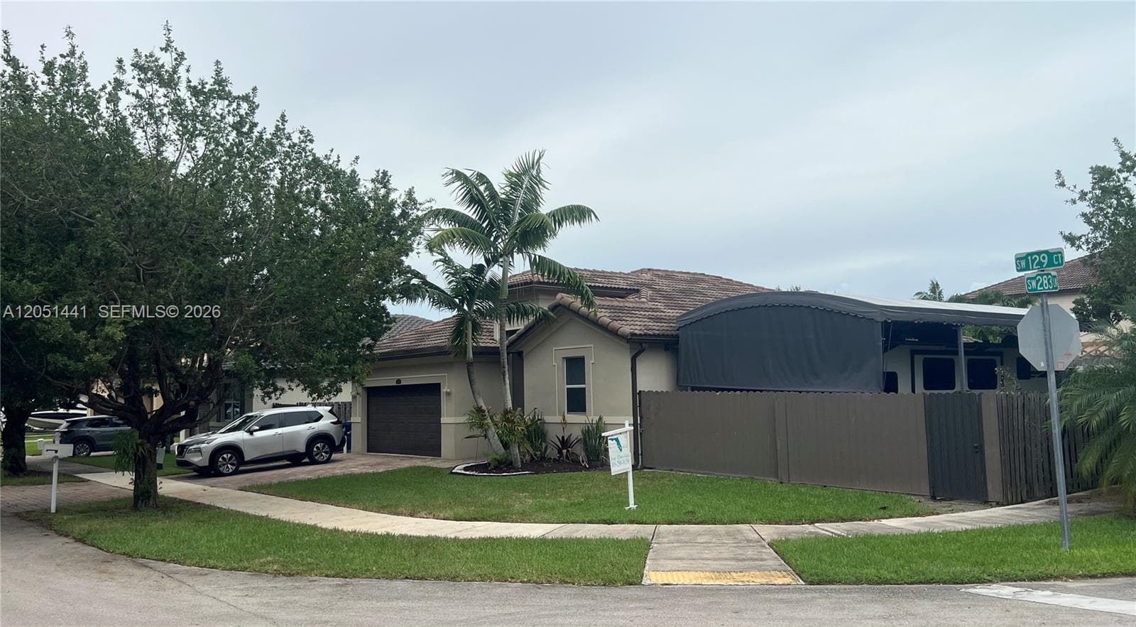 Stucco exterior with a tiled roof, attached garage, and privacy fencing
