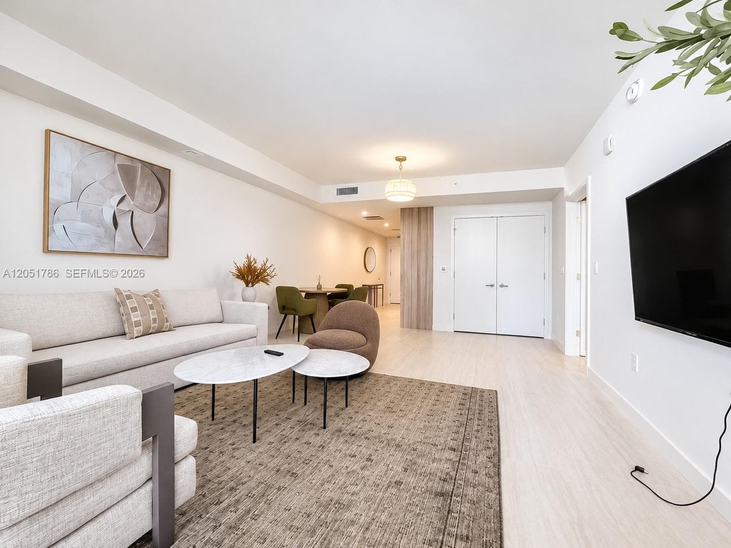 Open-concept space featuring light wood-finish flooring, recessed lighting, a modern pendant light fixture, and floor-to-ceiling double doors
