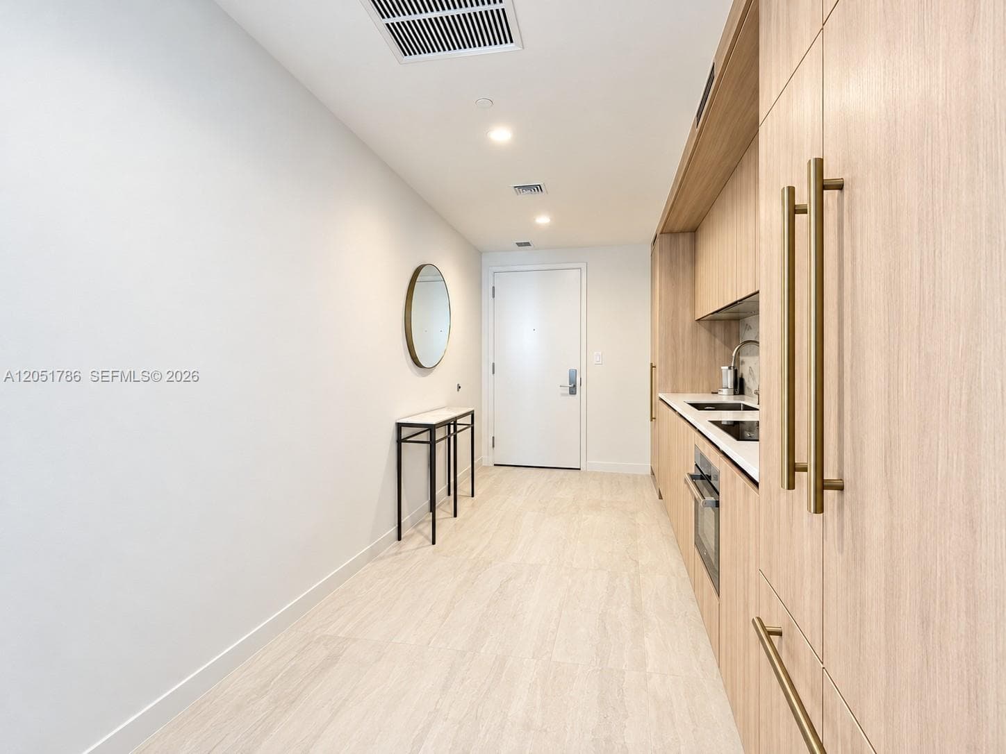 Kitchen featuring flat-panel wood-finish cabinetry, brass-toned hardware, solid-surface countertops, and recessed lighting